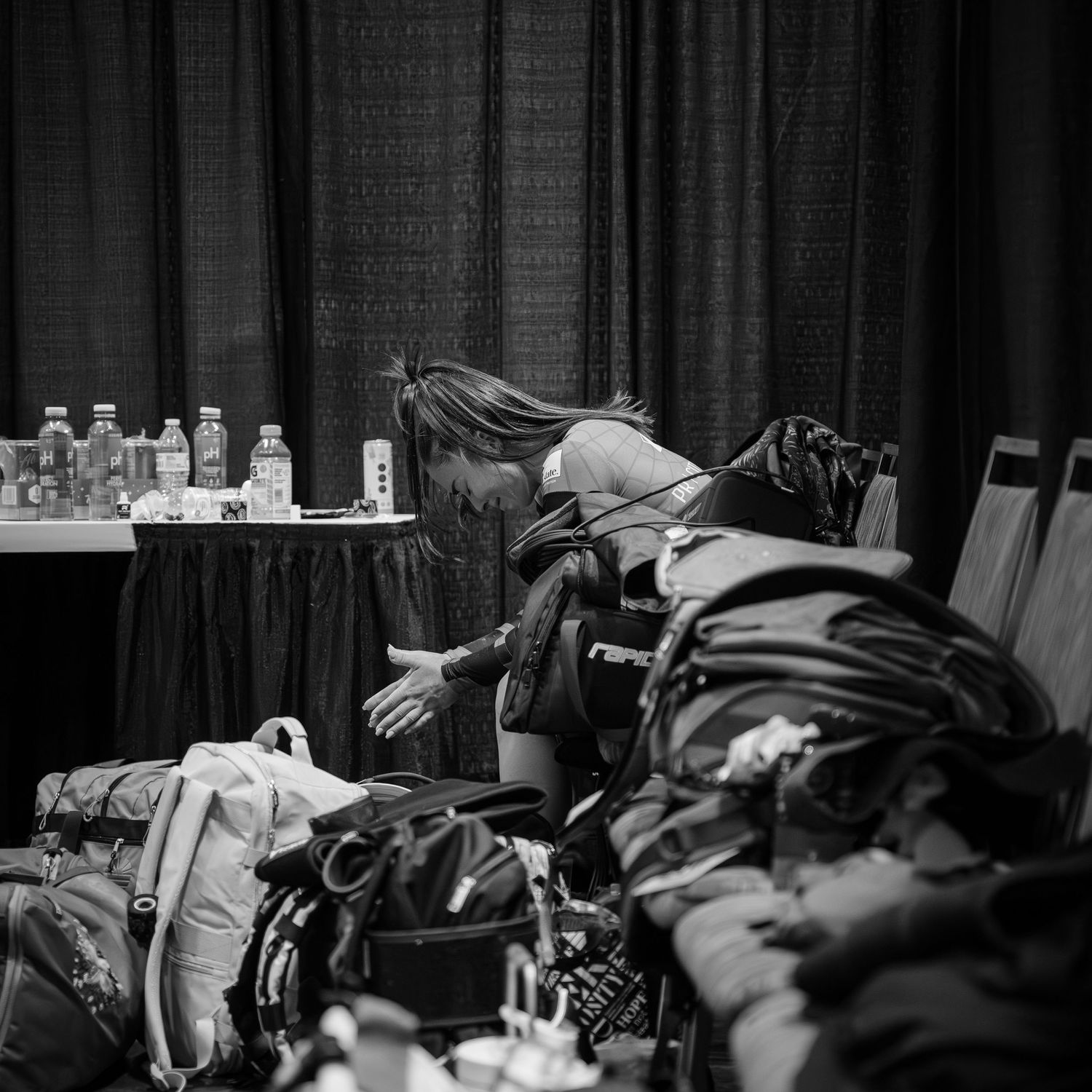 Black and white overhead shot of someone resting on gear and equipment backstage.