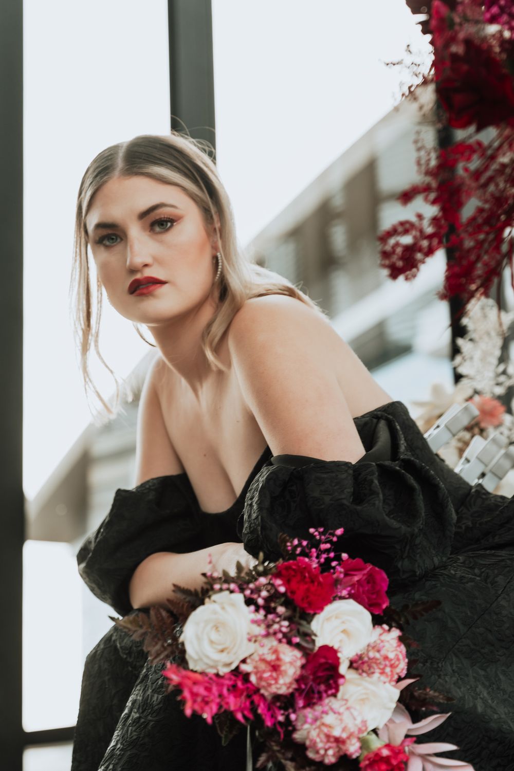 Elegant portrait in black off-shoulder dress with mixed rose bouquet.
