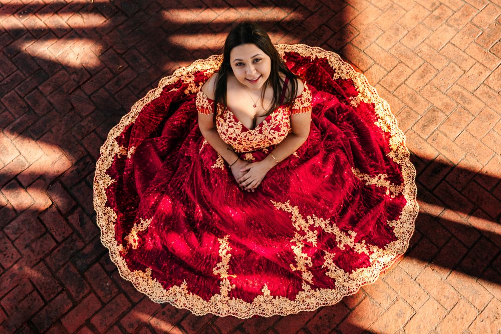 Overhead view of a person wearing an ornate red and gold traditional dress gown posed in circular formation.
