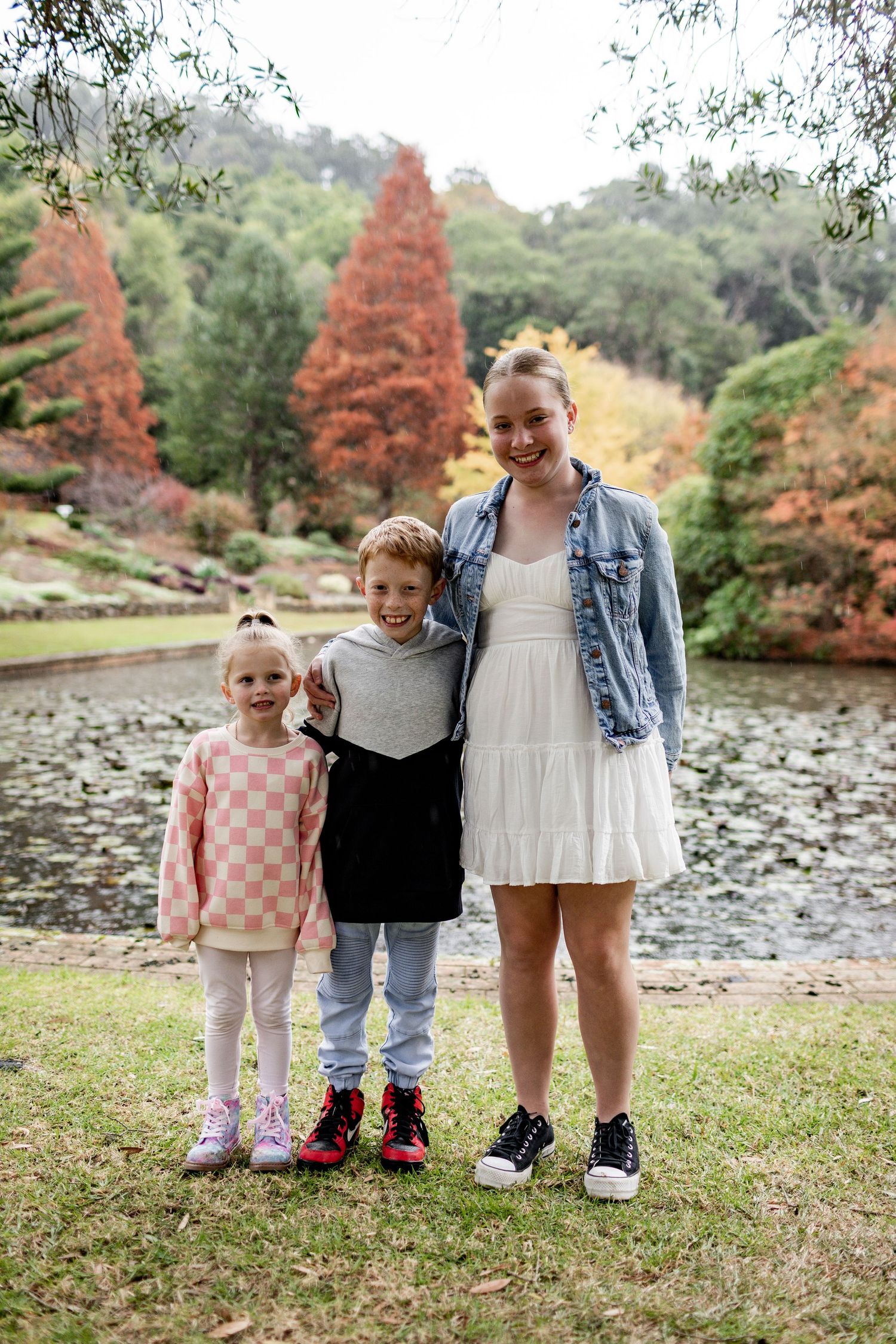 Group standing together by a pond with rust-colored trees in the background.