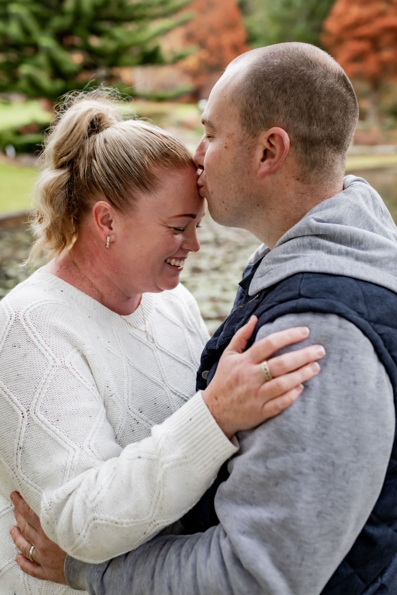 A tender moment captured between two people embracing by an autumn lake.