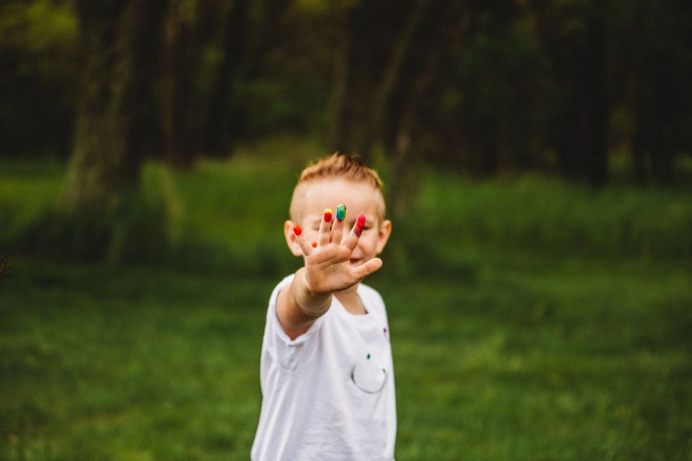 White t-shirts with colorful paint handprints and stains in outdoor setting.