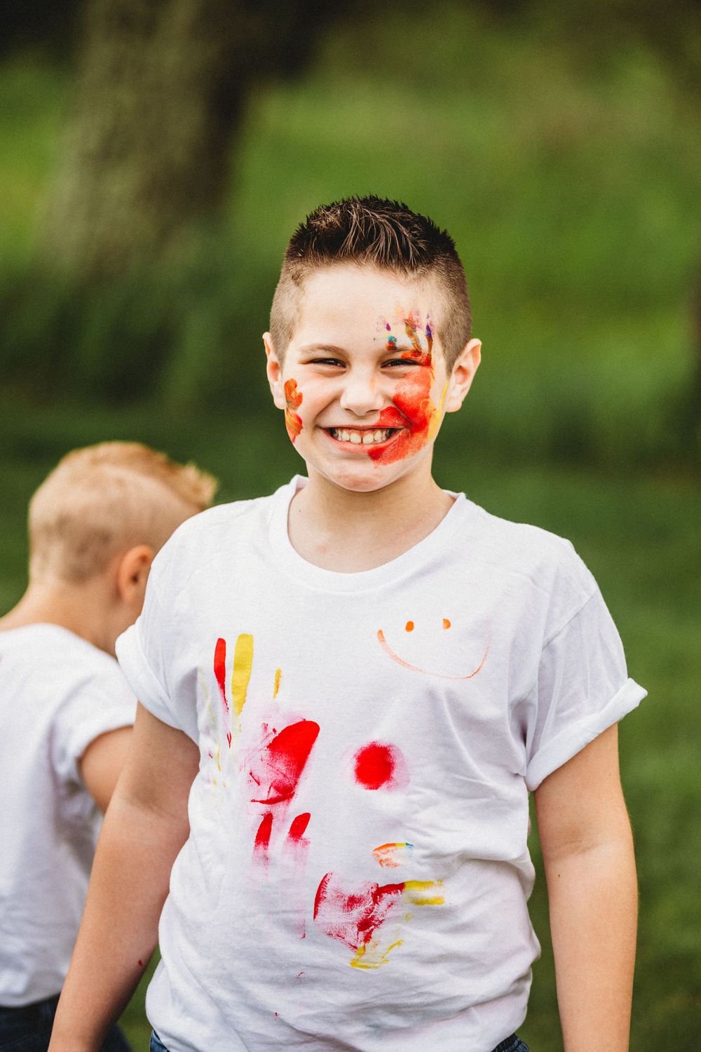 Paint-splattered white t-shirts against green natural background.