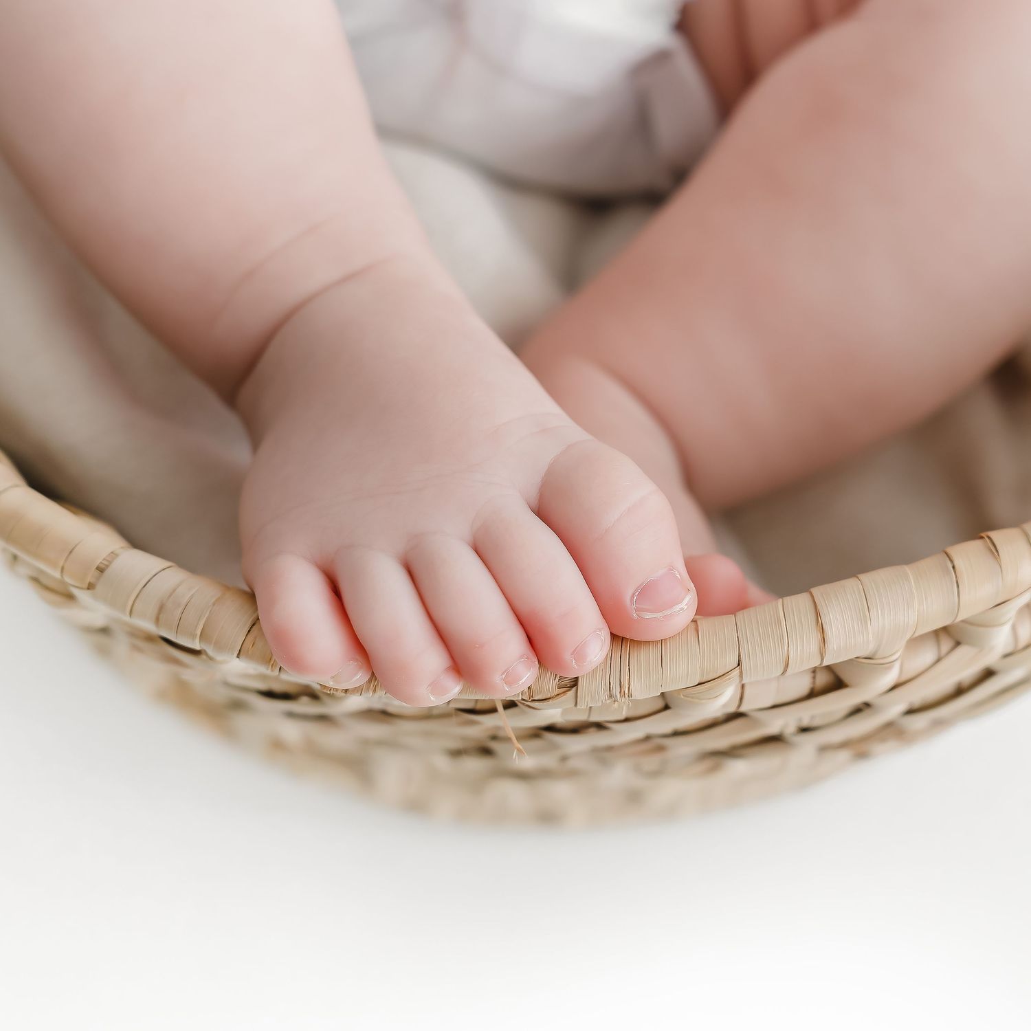 Close-up of delicate baby toes in a woven basket with soft fabric.