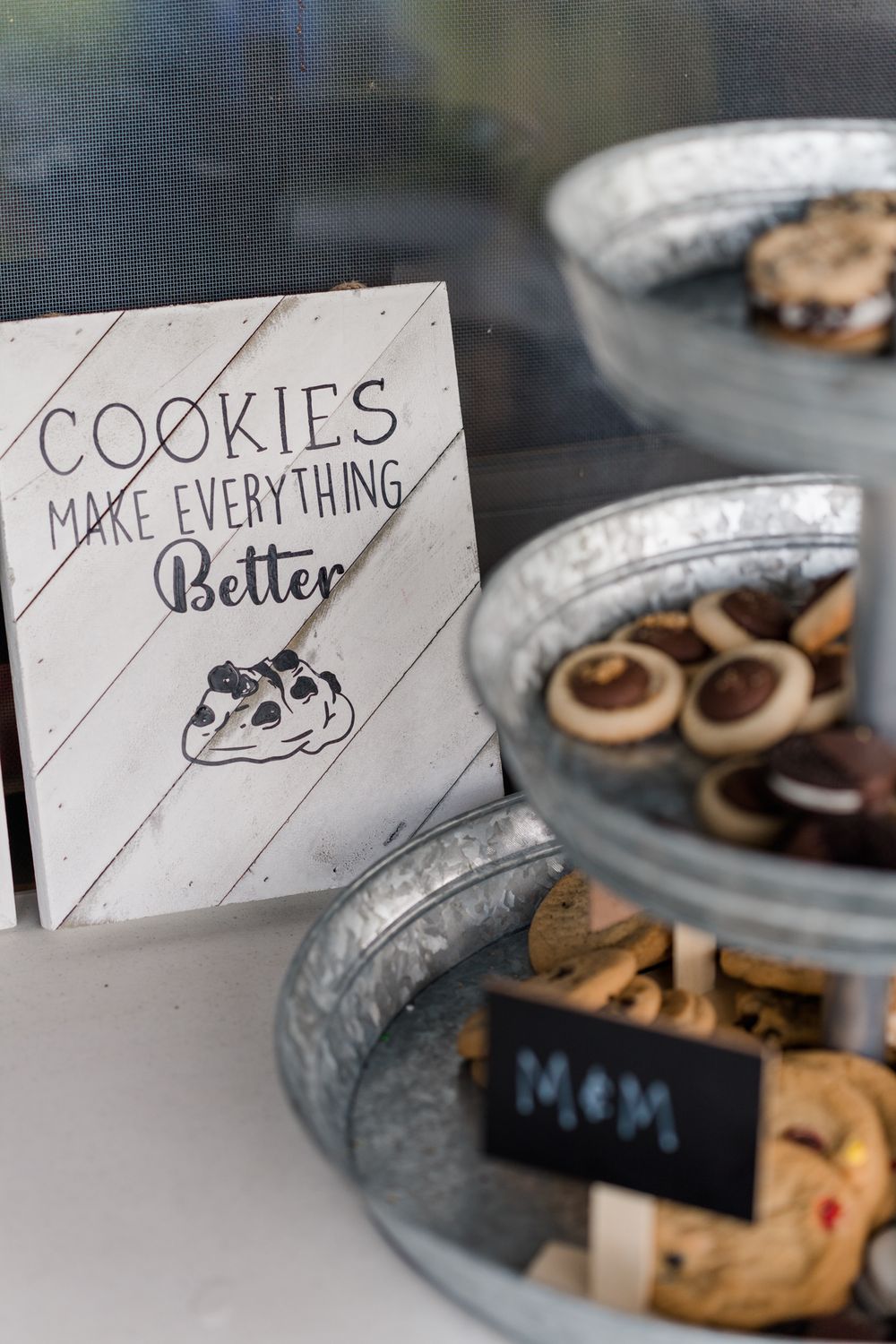 Cookie display with handwritten sign and tiered glass containers filled with various homemade treats.