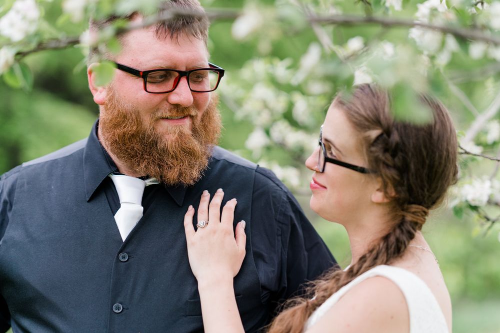 A tender moment captured between a couple beneath blooming spring branches.
