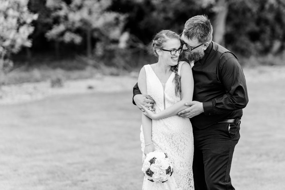 A black and white wedding portrait shows a tender moment between newlyweds.