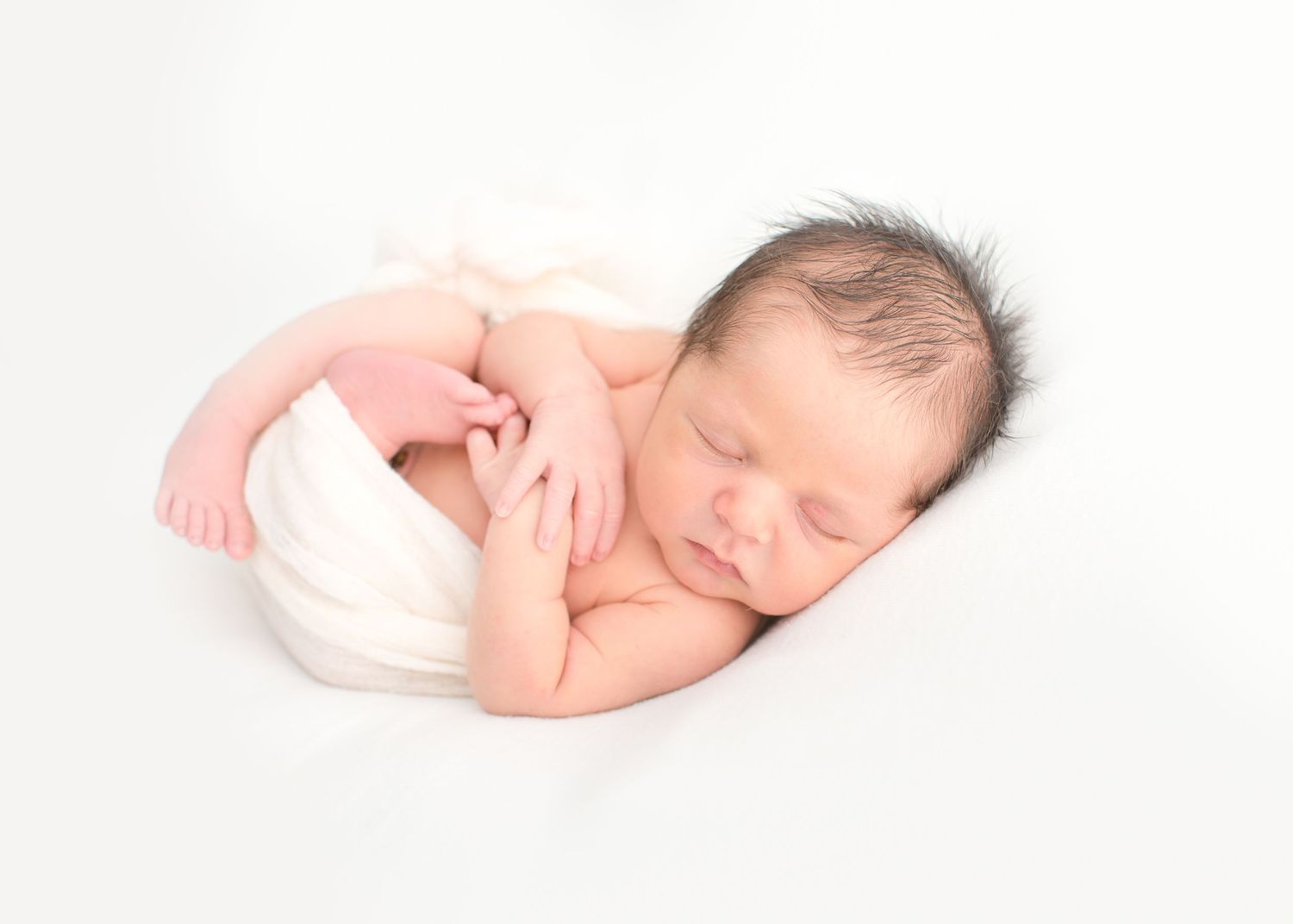 baby is wrapped in a beautiful linen color posing for a newborn all white natural light photography session in houston