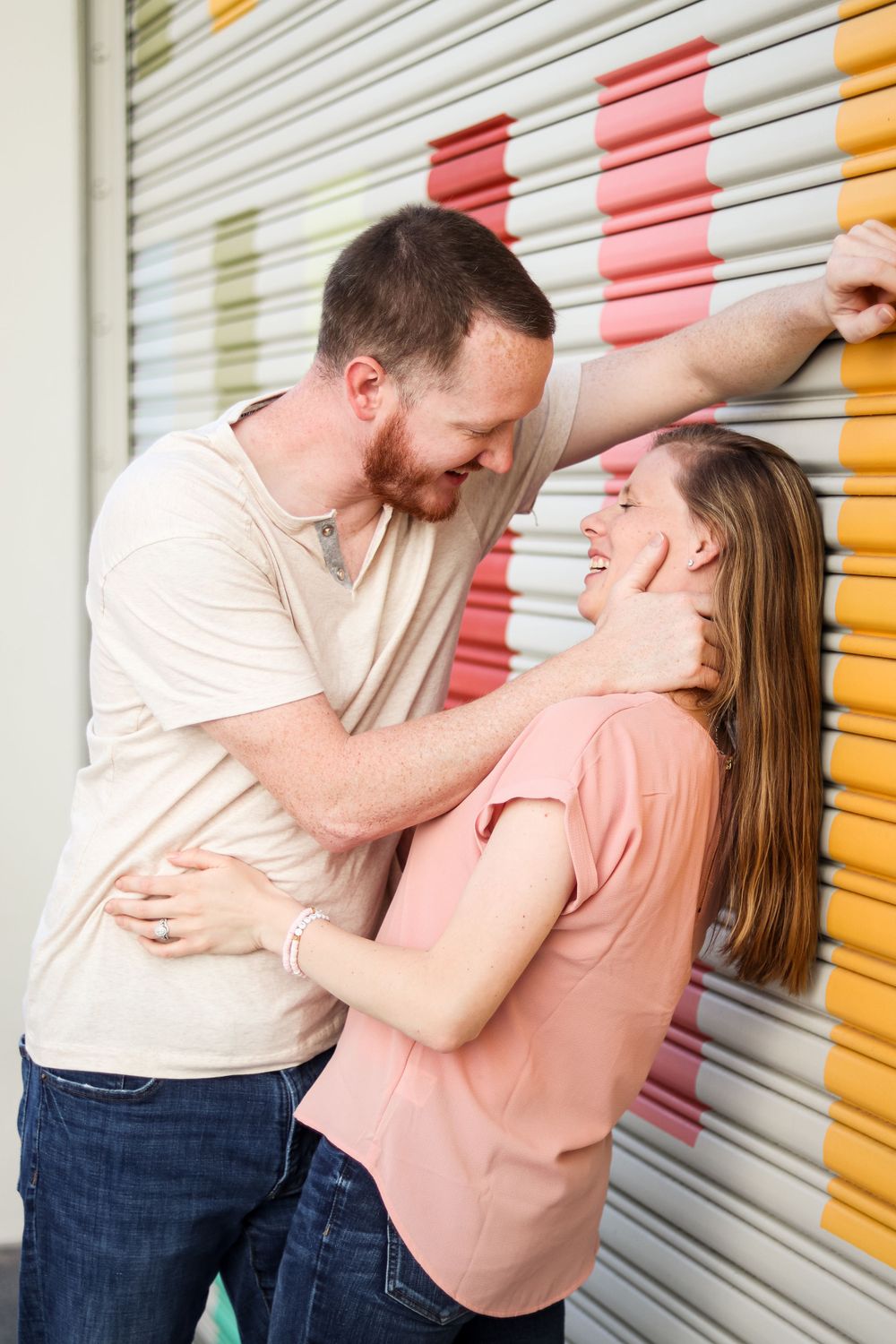 Playful couple interacts against a colorful striped wall background.