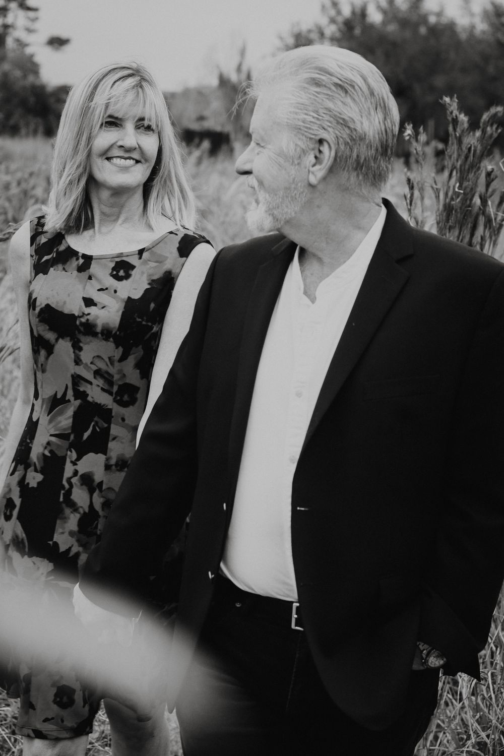 A couple wearing black and red outfits embrace warmly outdoors during a photo session.