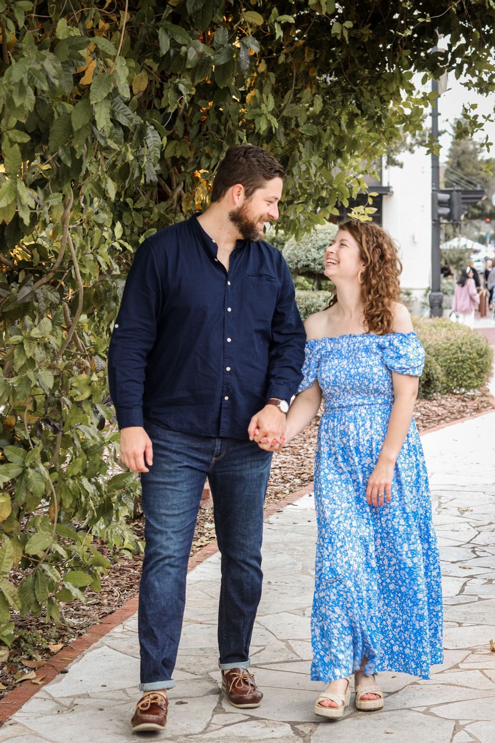 A couple in blue dress and navy shirt share intimate moments on a stone path.