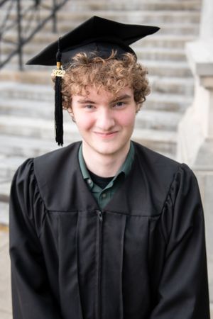 A graduate in black cap and gown during a graduation photo session.