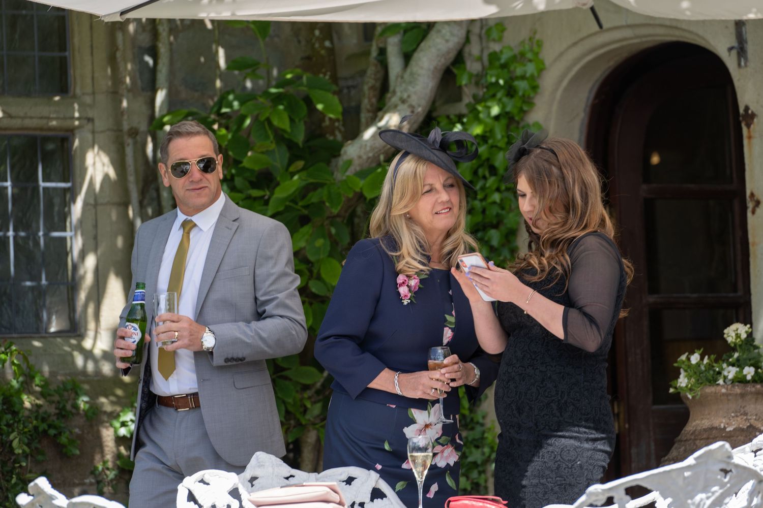 Wedding guests mingling during an outdoor reception near an elegant archway.