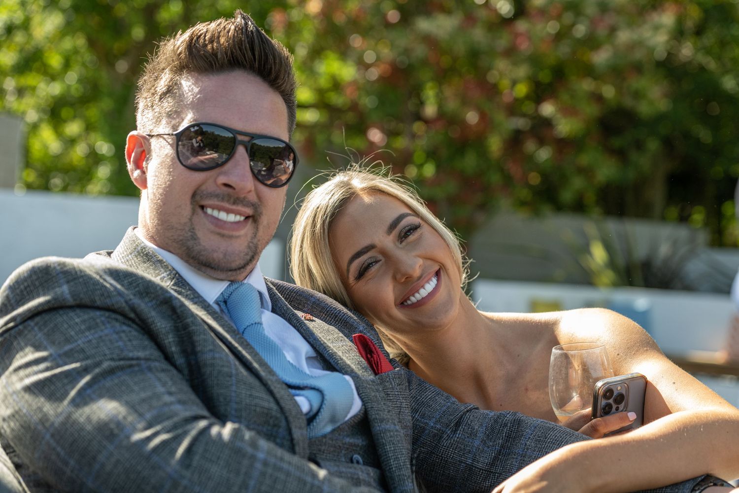 A happy couple in formalwear relaxing outdoors on a sunny day.