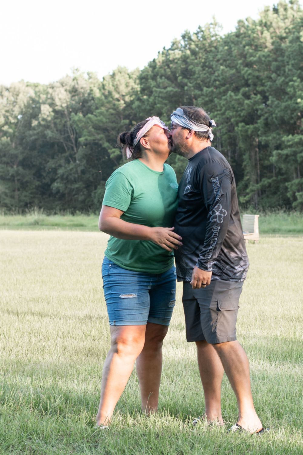 A couple sharing an intimate moment in a sunlit meadow.