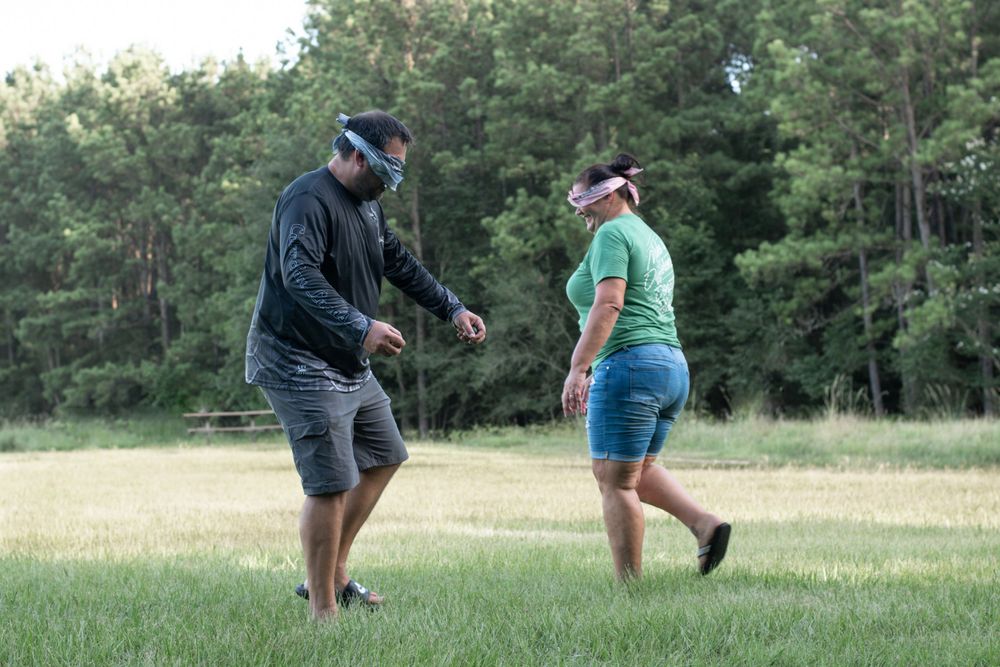 Two people dancing or playing a game together in a grassy field.