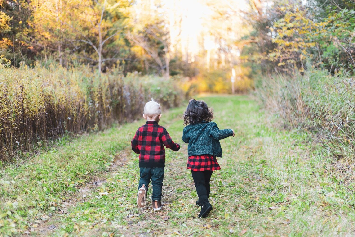 two young kids (boy and girl) running in a field