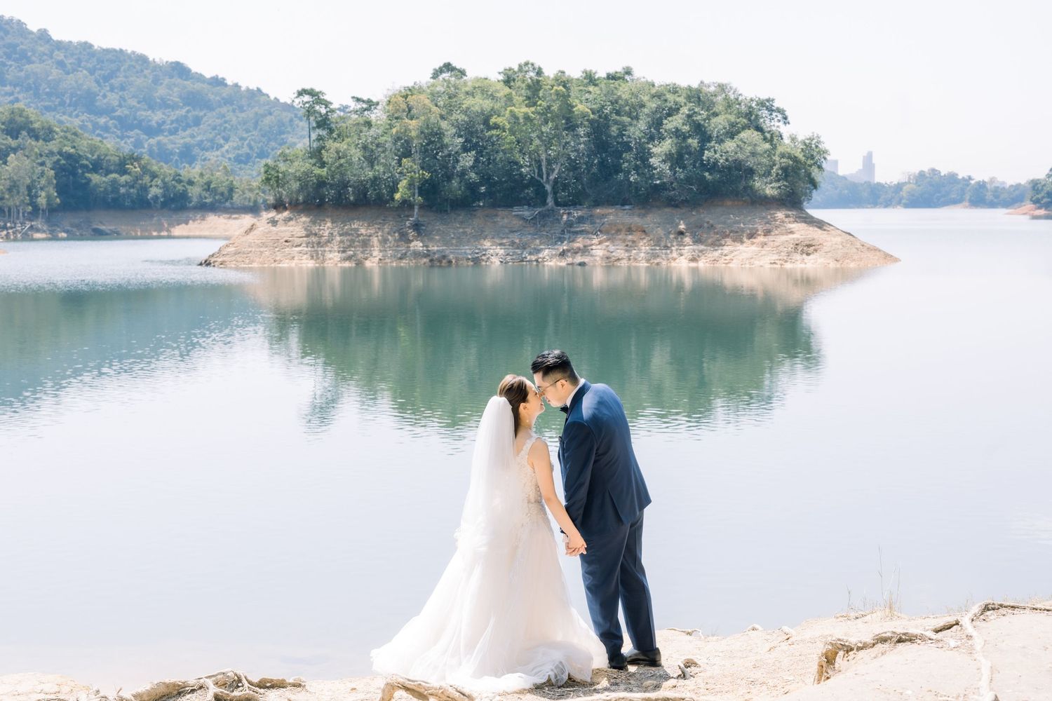 Scenic lakeside wedding photo with mountains and water in the background.