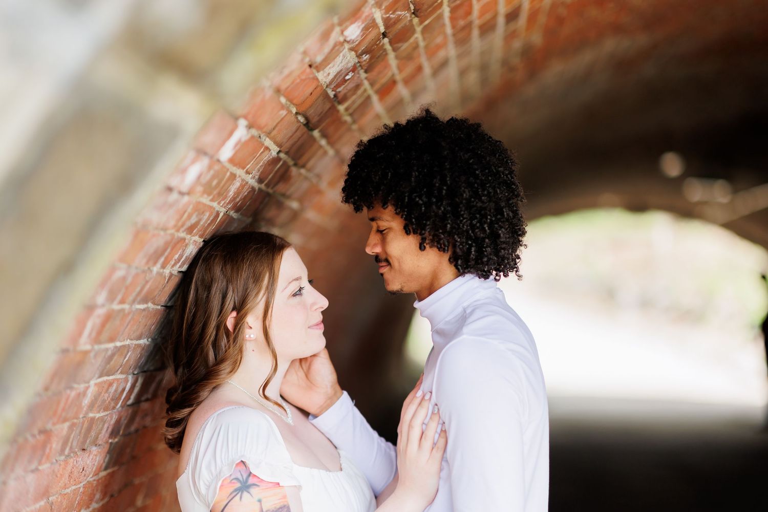 Romantic engagement photo taken against brick wall background.