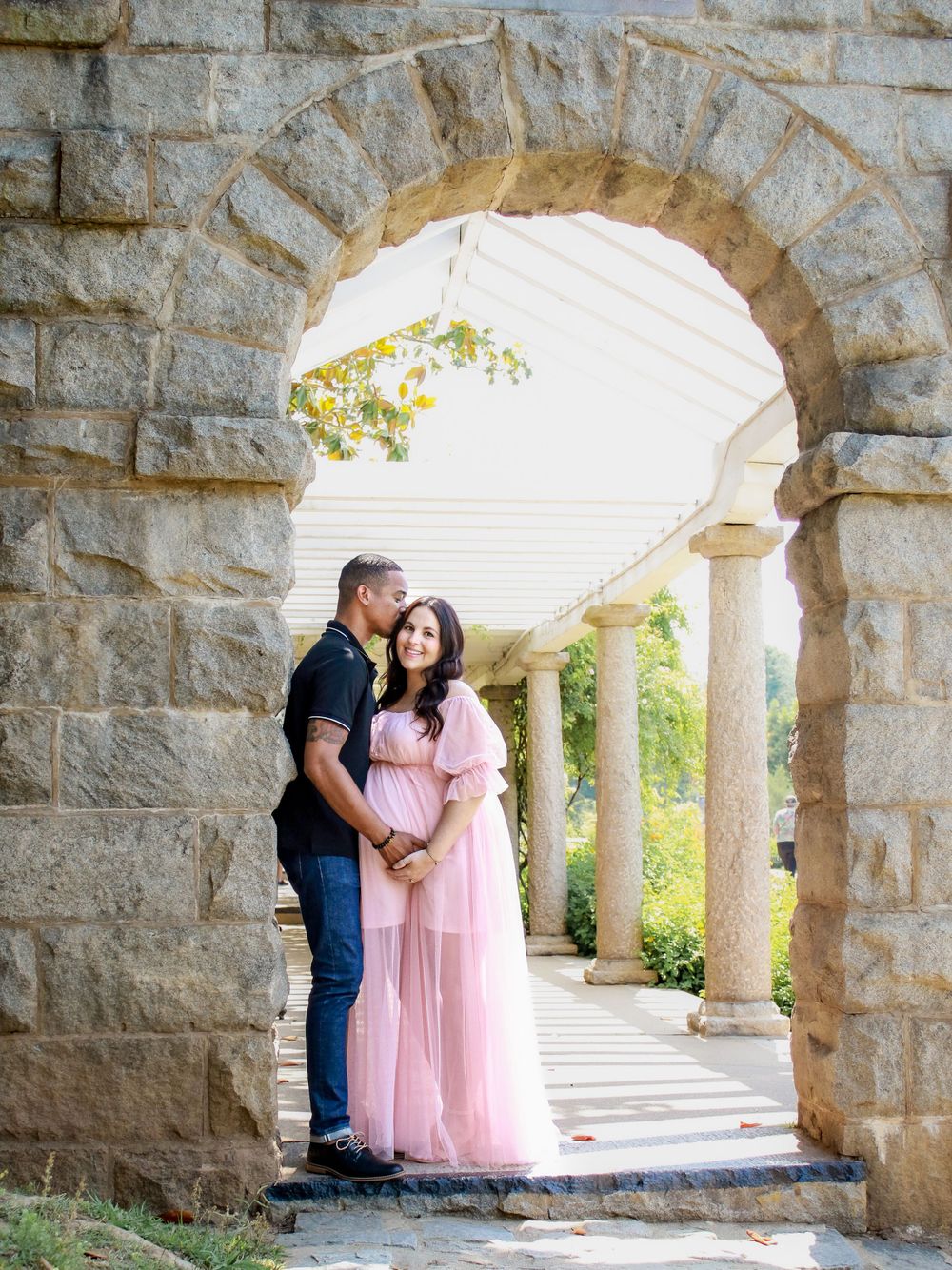 Stone archway engagement session with pink dress and romantic pose.