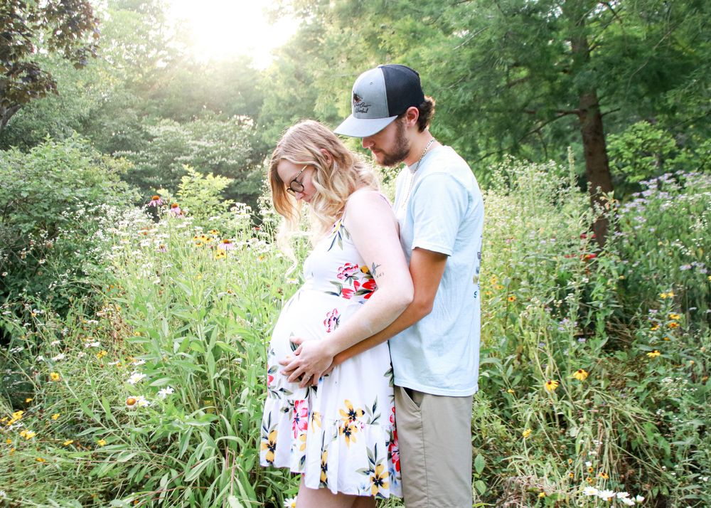 Romantic outdoor photoshoot in a lush garden setting with natural sunlight filtering through trees.