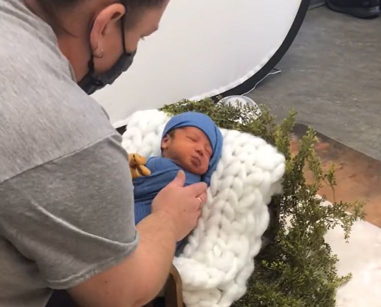 Professional photographer adjusting lighting during newborn photo session.