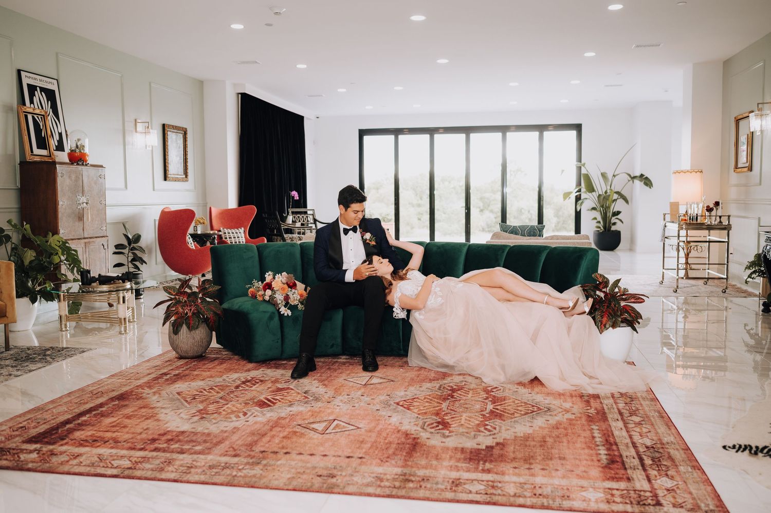 Elegant living room scene featuring a vintage red velvet couch and ornate Persian rug in a modern minimalist space.