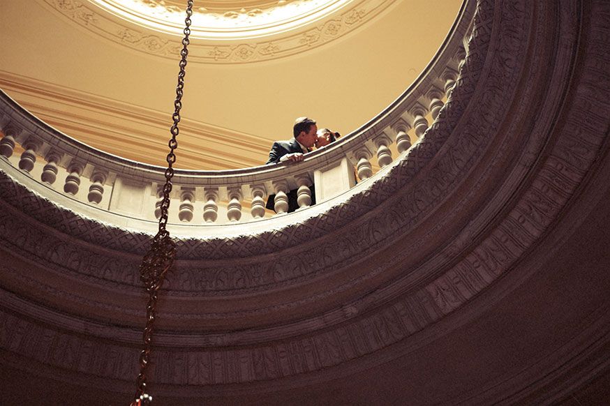Architectural photo looking up at a circular balcony with ornate details and warm lighting.