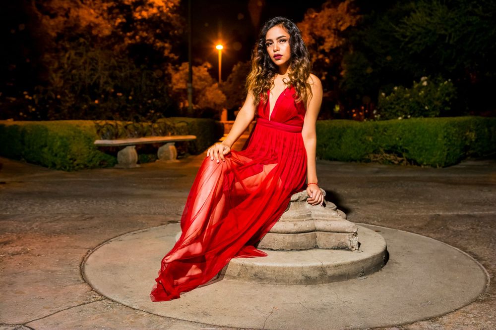 Elegant red dress photoshoot on concrete steps at night with warm lighting.