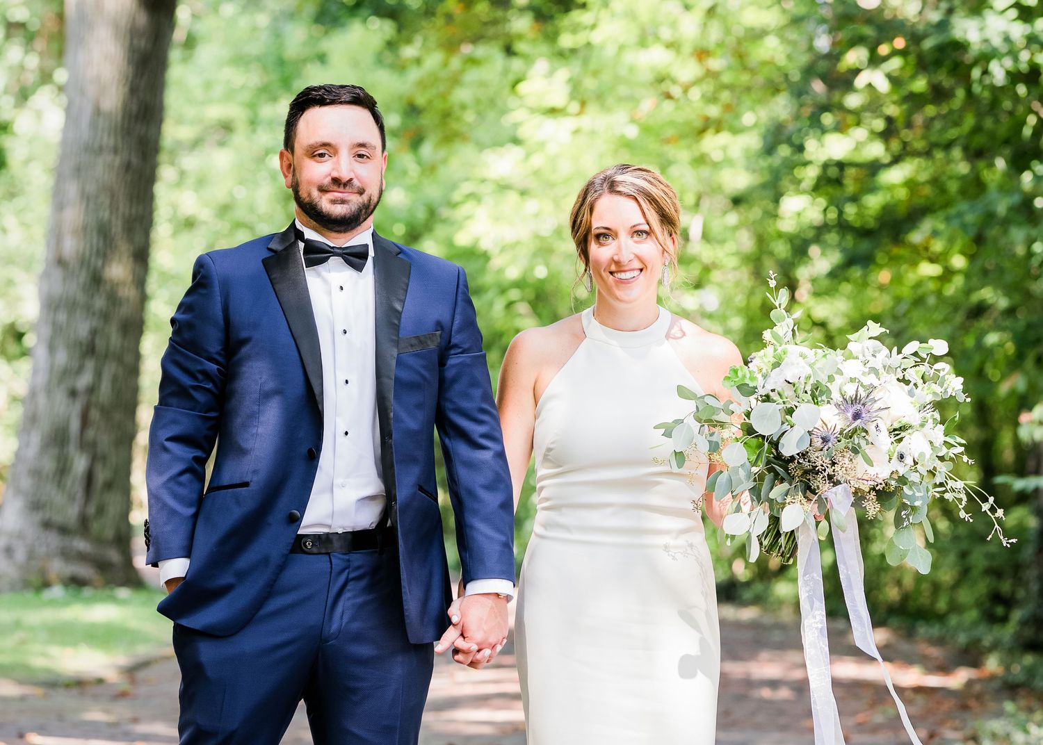 bride and groom walk down brick driveway with flowers