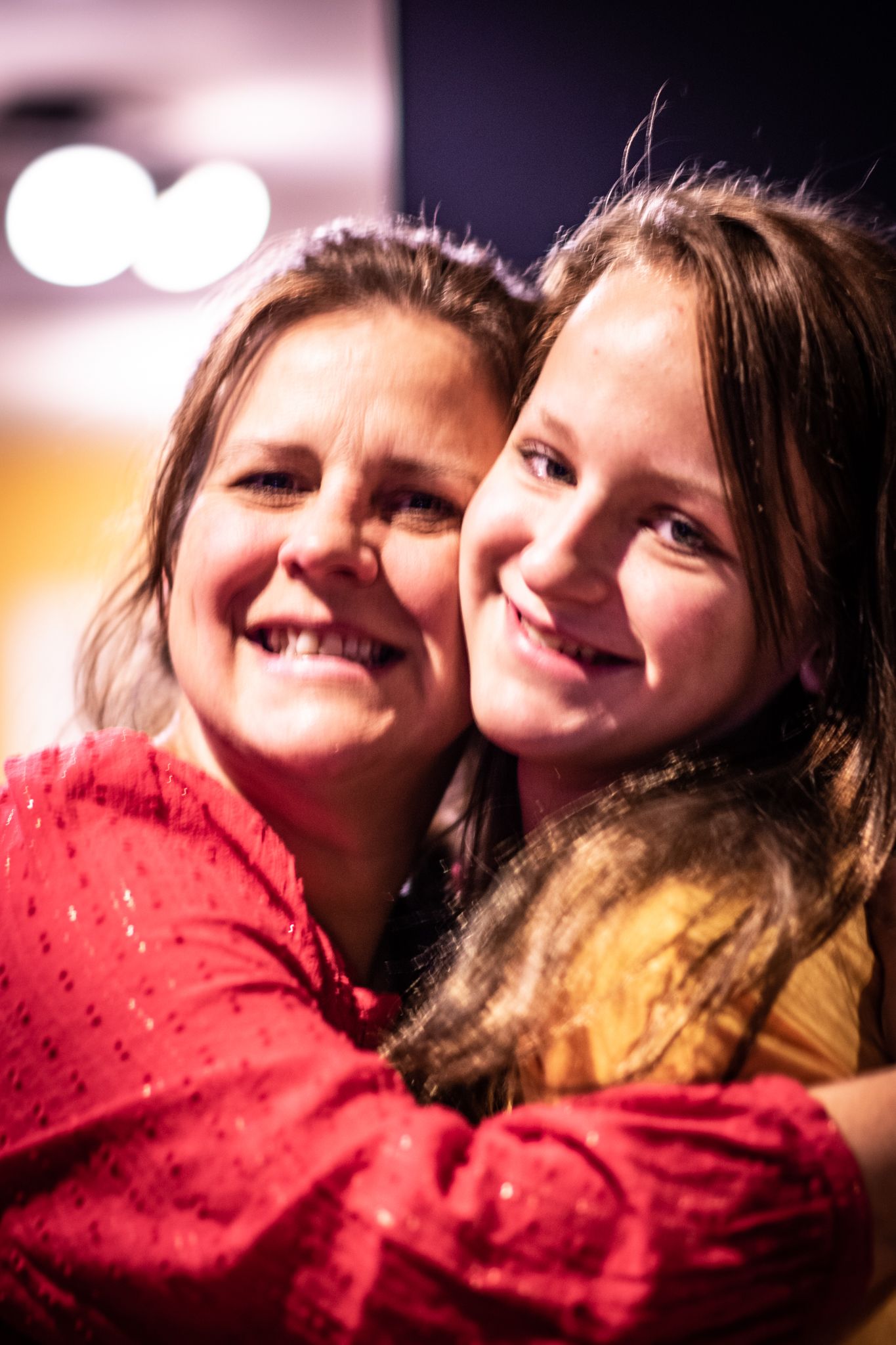 Joyful moment captured in portrait with bokeh lights in background.