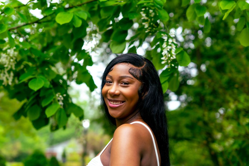 Maternity portrait of woman smiling among flowering trees in natural setting.
