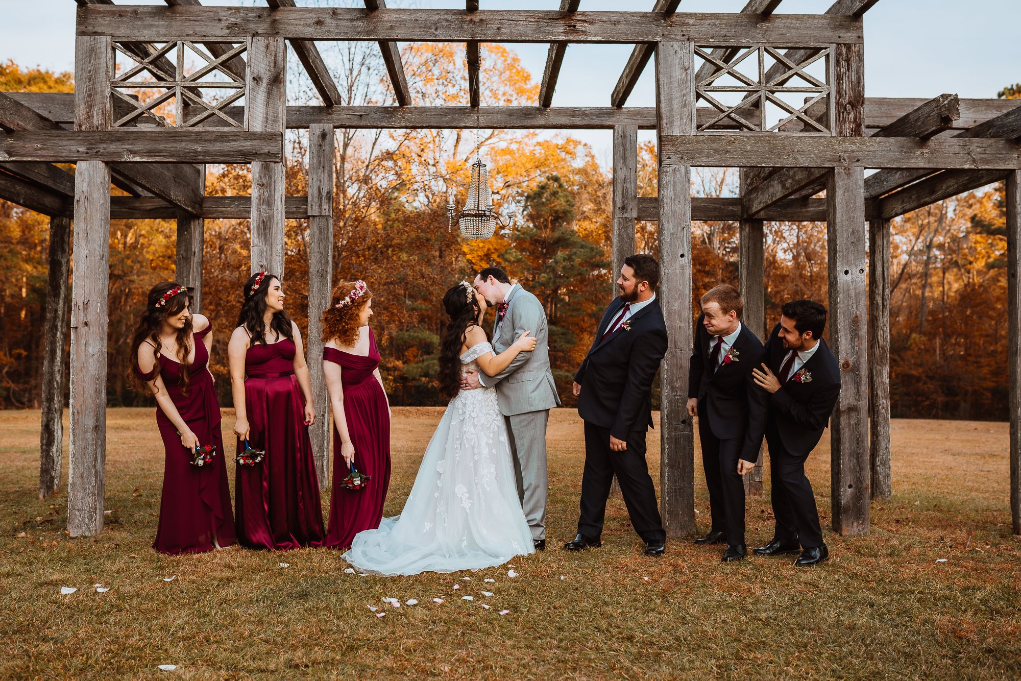 full wedding party with bride and groom kissing and cheering