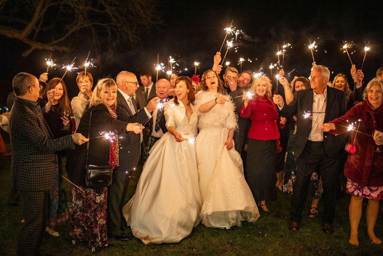 Wedding celebration at night with guests holding sparklers creating a magical atmosphere.