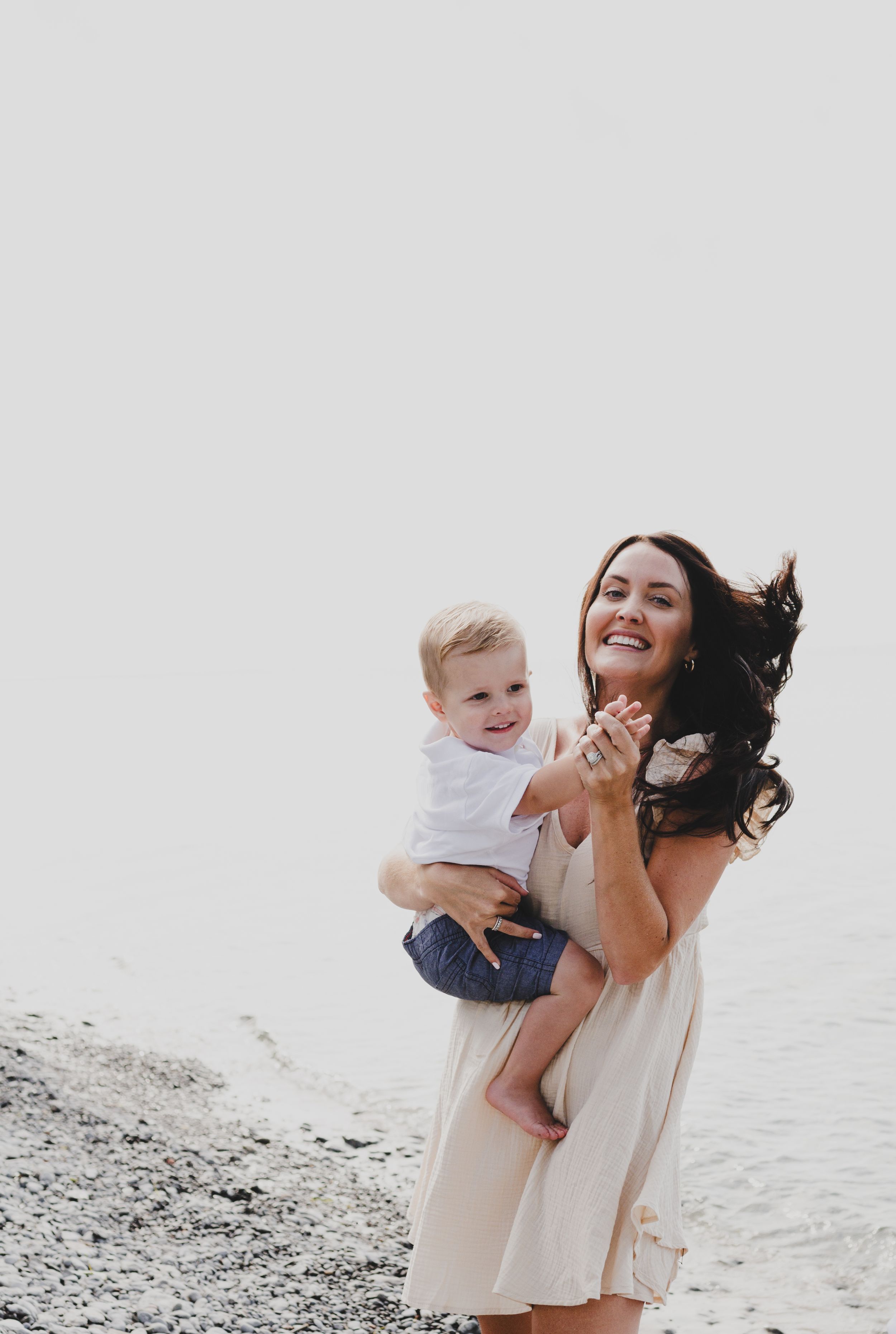 Mother and child sharing a joyful moment on a rocky beach.