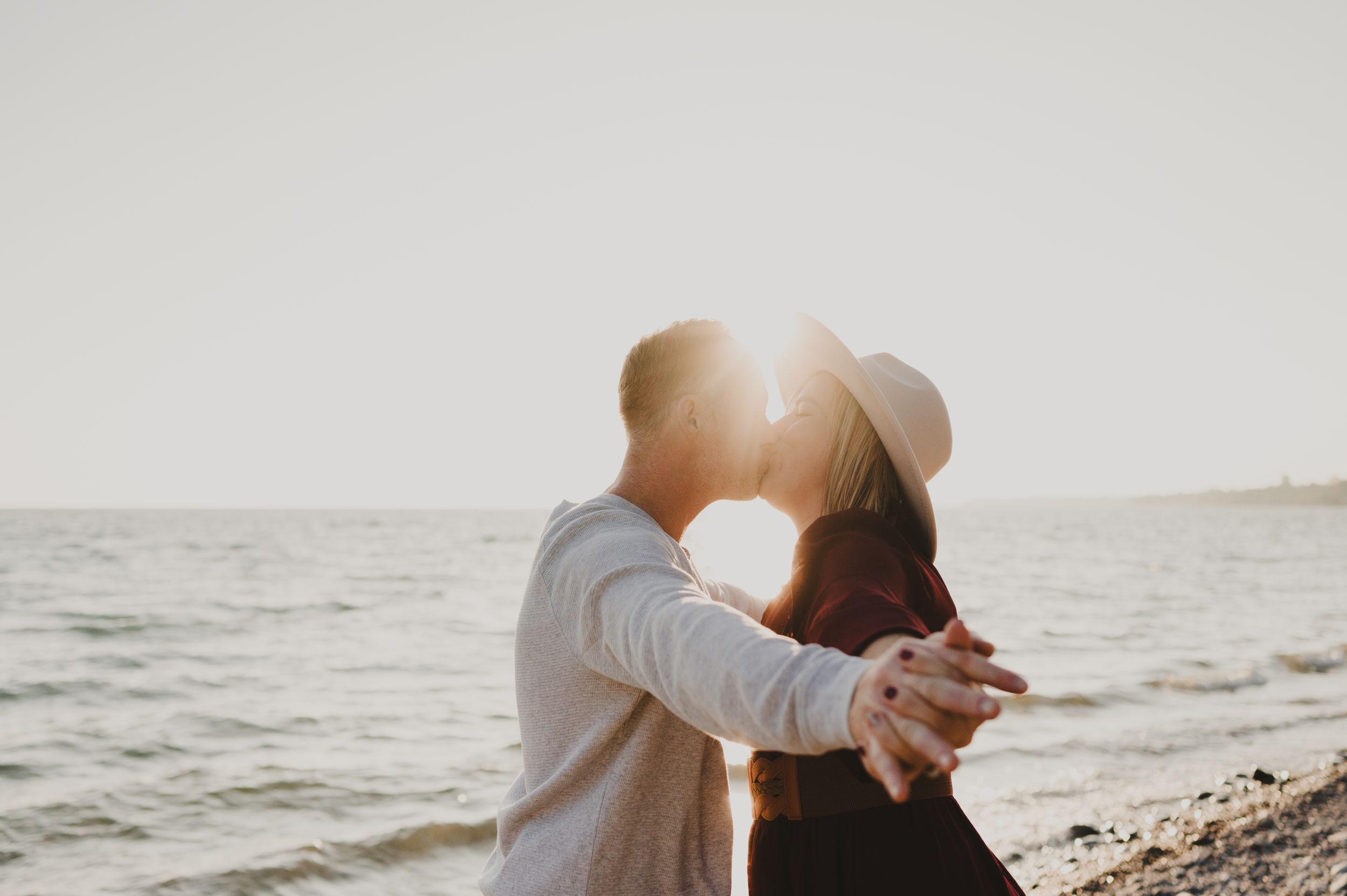 Silhouetted couple dancing together on a beach at sunset.