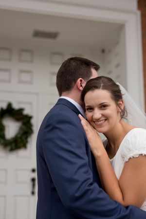 An intimate wedding portrait taken at a church entrance with decorative wreath.
