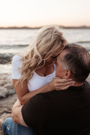 close up of a couple embracing, forehead to forehead at the lake during sunset
