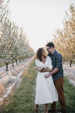 couple embracing in a almond orchard while in bloom