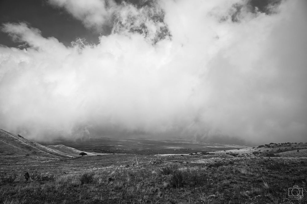 Black and white fisheye image of clouds over a valley