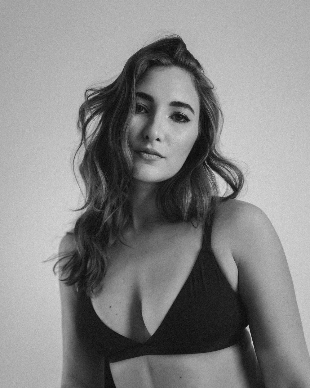 Black and white portrait of woman in athletic wear with natural wavy hair.