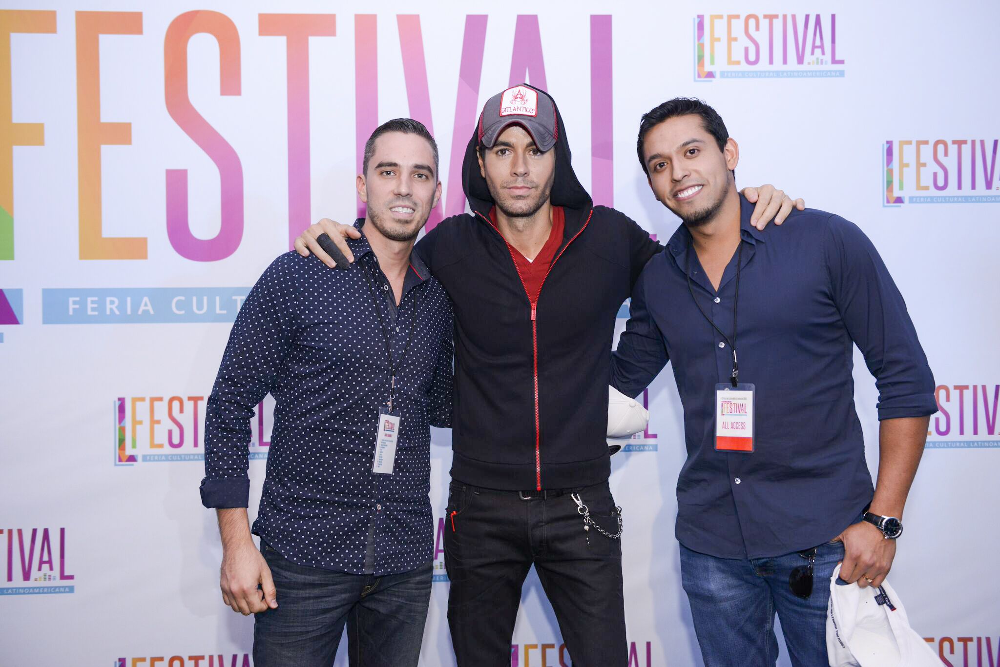 Group photo at a festival event with promotional backdrop displaying branding and logos.