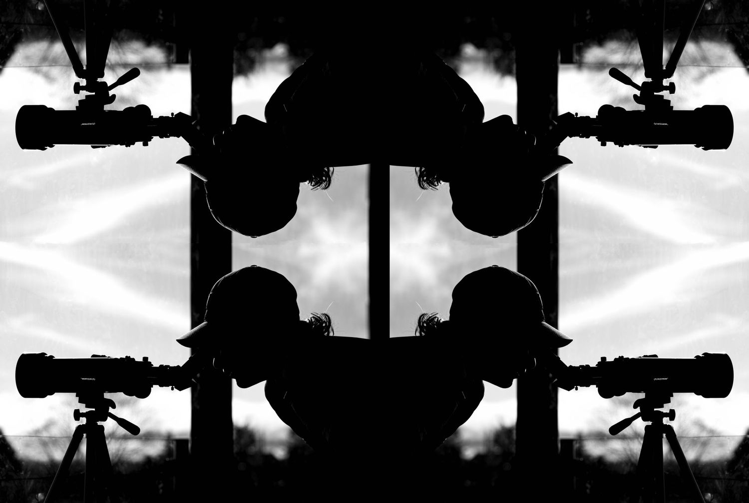 An art shot that is a black and white mirror image of a teen boy looking through a telescope.