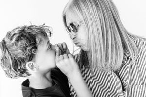 A grandma and her grandson make faces at each other during a Candid shoot against a white backdrop in West Seattle