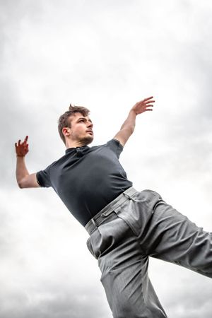 Male graduating senior and dancer poses on top of rocks along the shore at Lincoln Park, West Seattle.