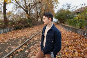 A teen in Georgetown, Seattle, stands in a denim jacket on fall leaves that cover old train tracks: Senior Session