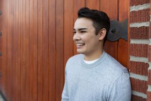 Graduating senior poses against a wood and brick garage in Georgetown, Seattle.