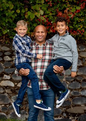 Dad holding his two sons up on his hips at a family photo shoot in Lincoln Park, West Seattle