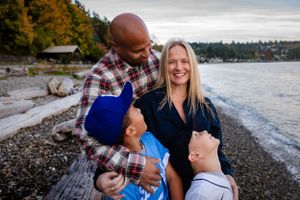 Dad and two sons look to a smiling mom in a family photo session at sunset in Lincoln Park, West Seattle.