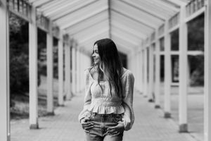 Black and white photo of a girl standing below a covered walkway in Seattle Center.